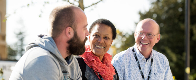 Three mature students chatting and smiling together.